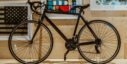 Black bicycle parked indoors against a wall with framed art, creating a stylish and modern look.